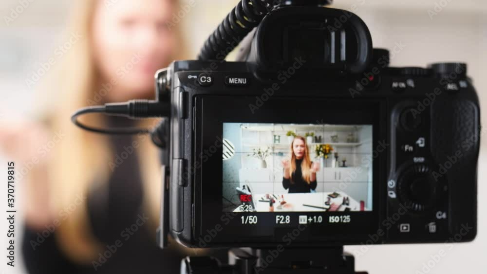 Vlogger female applies lipstick on lips. Beauty blogger woman filming daily makeup routine tutorial at camera on tripod. Influencer blonde girl live streaming cosmetics product comparison in studio Vlogger female applies lipstick on lips. Beauty blogger woman filming daily makeup routine tutorial at camera on tripod. Influencer blonde girl live streaming cosmetics product comparison in studio