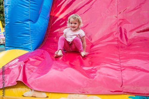 Wallpaper Mural Cute blonde girl riding an inflatable slide. C Torontodigital.ca