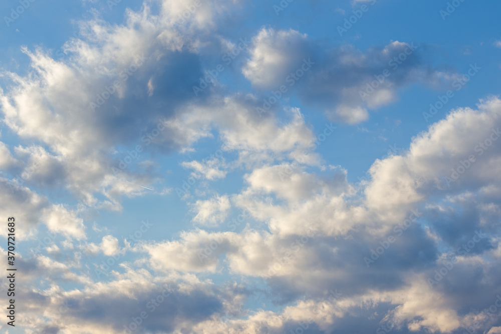 Obraz premium clouds in yellow sunset light. blue sky background in the evening