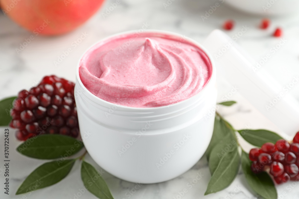 Fresh pomegranate and jar of facial mask on white marble table, closeup. Natural organic cosmetics Fresh pomegranate and jar of facial mask on white marble table, closeup. Natural organic cosmetics