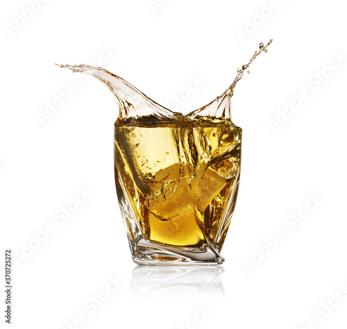 Whiskey splashing in glass on white background