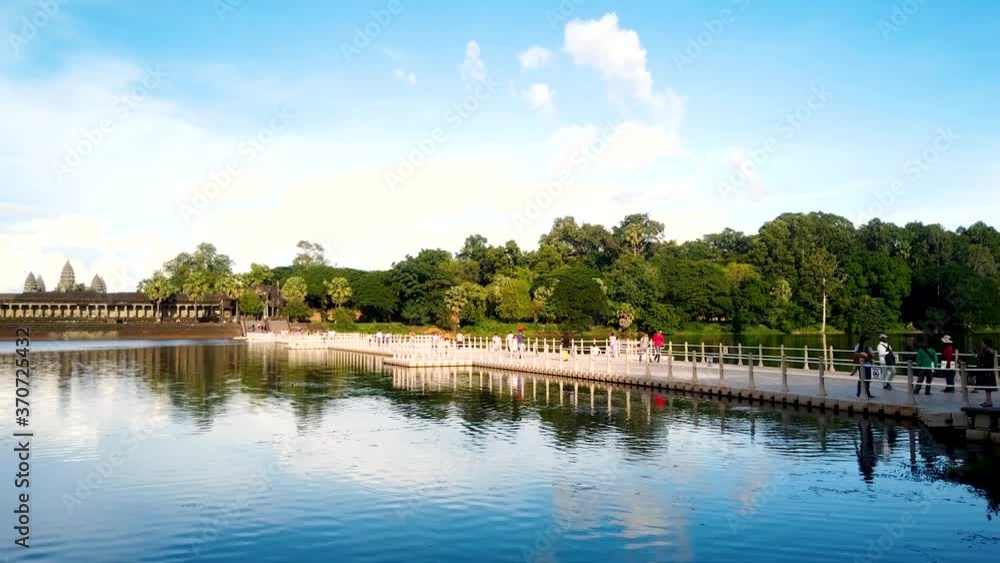 Time lapse of tourists and devotees on the bridge besides the pond, leading towards Angkor Wat temple complex in Cambodia. Time lapse of tourists and devotees on the bridge besides the pond, leading towards Angkor Wat temple complex in Cambodia.