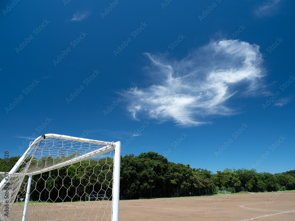 Fototapeta premium 真夏の青空と土のサッカーコートの風景