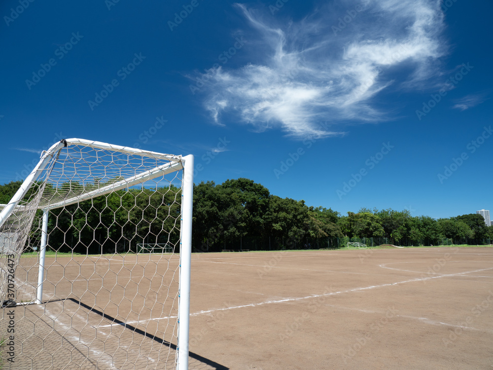 真夏の青空と土のサッカーコートの風景