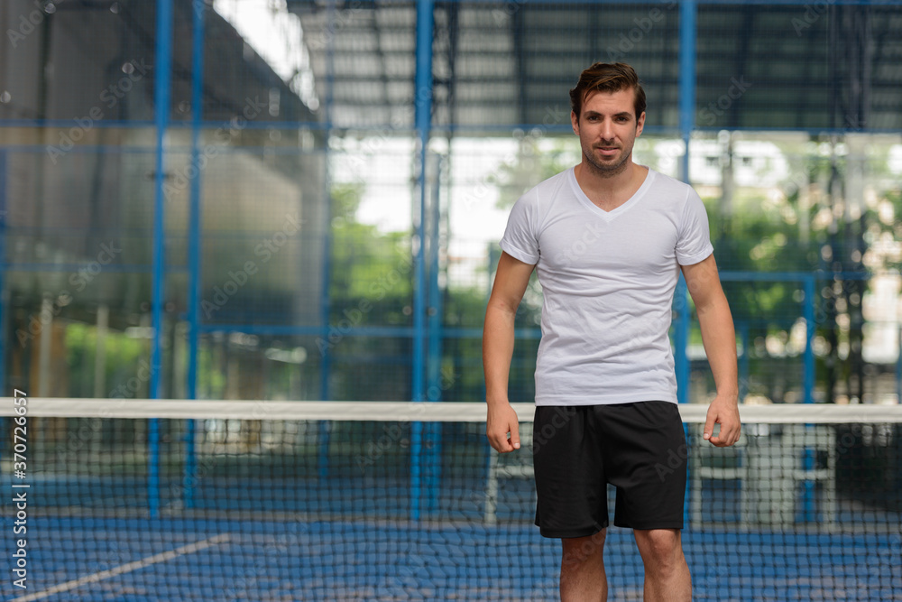 Young handsome Hispanic man at the padel court