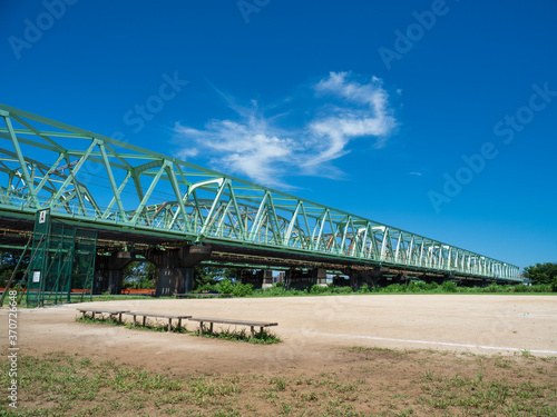8月の青空と河川敷の野球場と鉄橋。