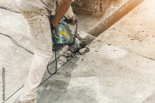 Construction worker using jackhammer drilling concrete surface