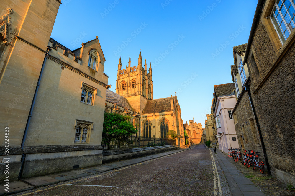 Merton College Chapel, down a side street, in Oxford at sunrise with no people around, early in the morning on a clear day with blue sky. Oxford, England, UK.