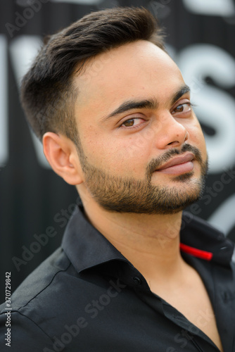 Young handsome bearded Indian businessman in the city