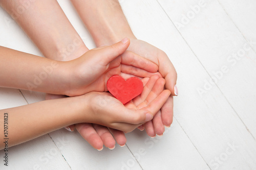 Obraz na plátně Human hands holding, giving heart isolated on white wooden background