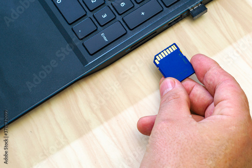 a man's hand inserting a flash card into the laptop connector