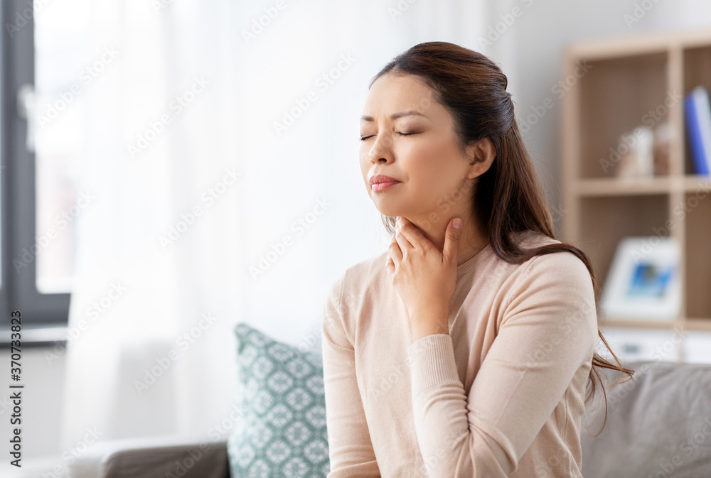 health, cold and people concept - sad sick young asian woman with sore throat at home health, cold and people concept - sad sick young asian woman with sore throat at home