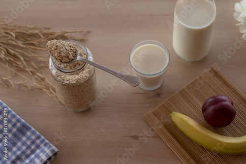 Mesa de madera con el desayuno con un bote de avena leche y fruta vista desde arriba