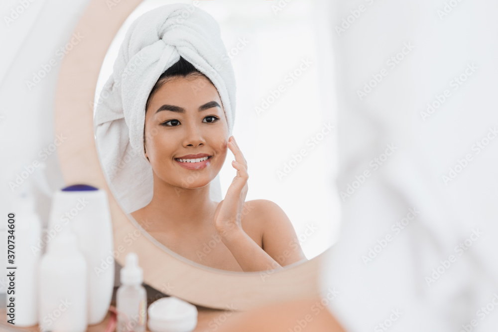 Cheerful asian young woman applying beauty product