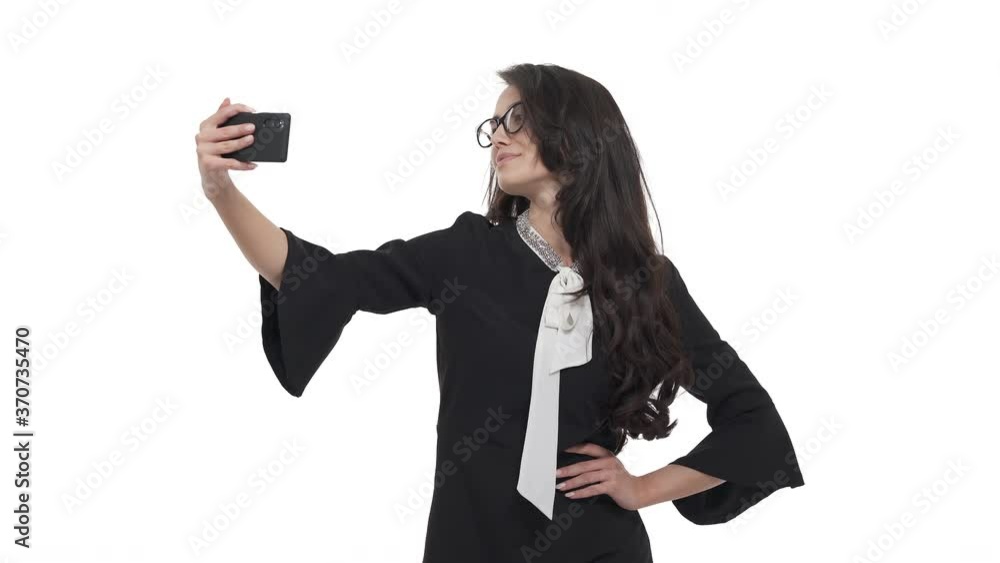 Portrait of young Caucasian woman in glasses taking selfie, posing on Smartphone camera. Isolated on white background.
