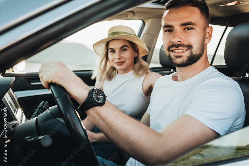 Happy Young Couple Sitting Inside Their Car and Enjoying Road Trip, Travel and Adventure Concept Happy Young Couple Sitting Inside Their Car and Enjoying Road Trip, Travel and Adventure Concept