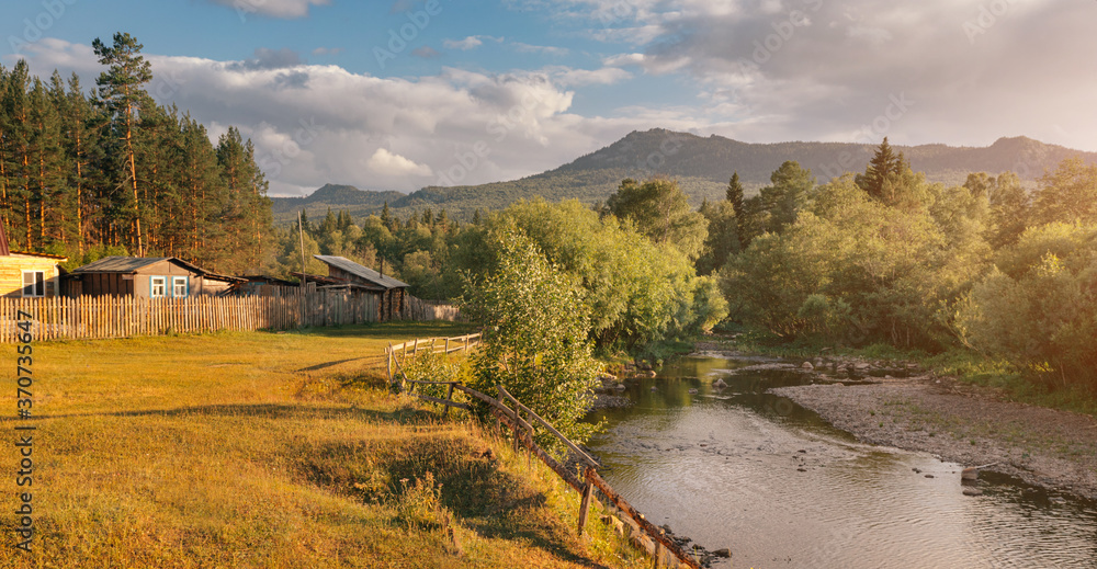 Obraz premium Panoramic landscape of taiga forest and a low mountain or hill. Small farm house near wild clean river