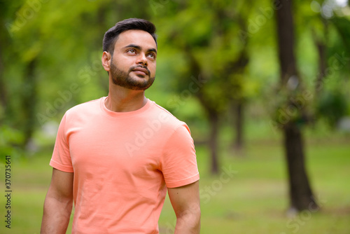 Young handsome bearded Indian man at the park