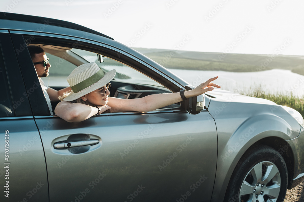 Happy Young Couple Sitting Inside Their Car and Enjoying Road Trip, Travel and Adventure Concept Happy Young Couple Sitting Inside Their Car and Enjoying Road Trip, Travel and Adventure Concept