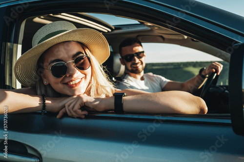 Happy Young Couple Sitting Inside Their Car and Enjoying Road Trip, Travel and Adventure Concept