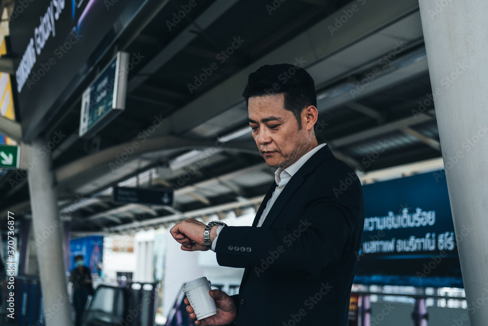 Business man looking at his watch while waiting at train station stock photo Business man looking at his watch while waiting at train station stock photo