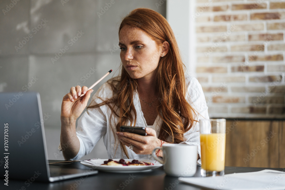 Image of businesswoman working with laptop while having breakfast Image of businesswoman working with laptop while having breakfast