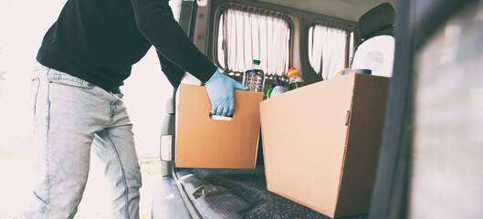 The courier takes the cardboard eco box with products from grocery shop out  from the van