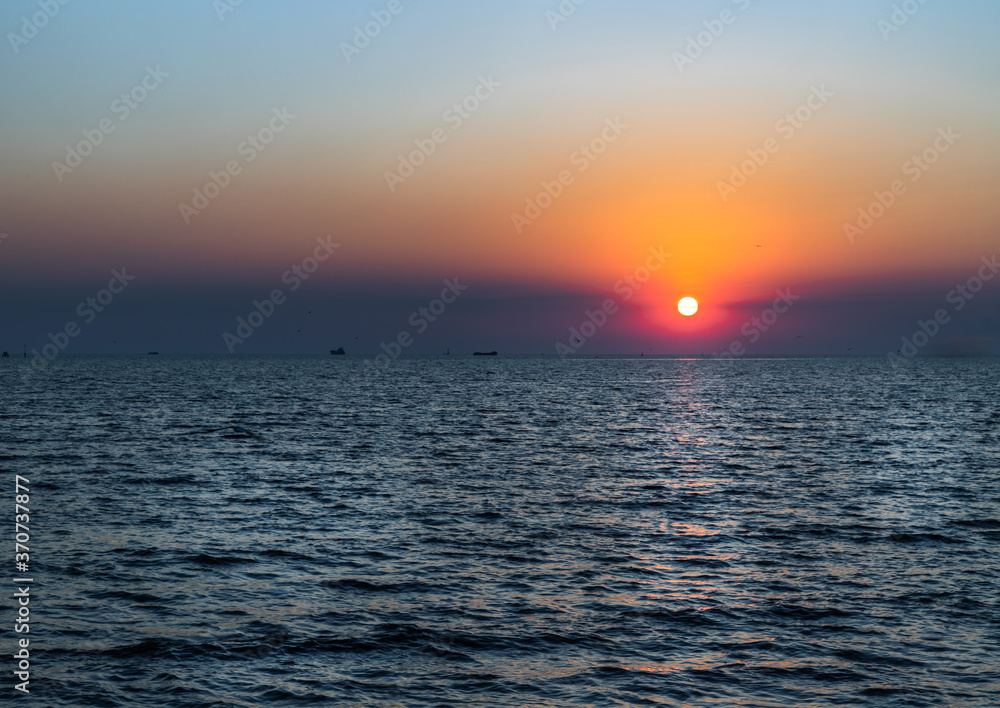 Beautiful sunset over a calm sea with a blue and orange glowing sky. Space for text, Selective focus. 