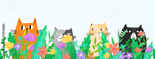 Funny cats sitting in the grass and flowers.