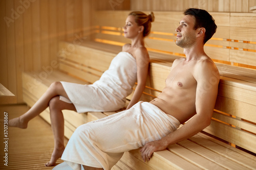 Foto Smiling man day dreaming while relaxing in sauna at the spa.