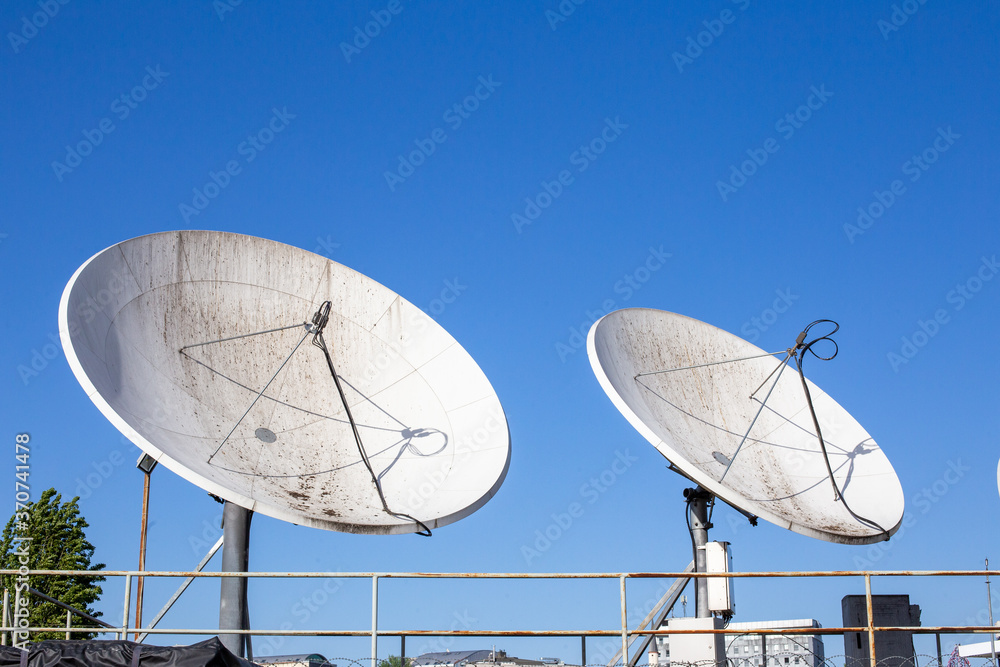 A group of dirty satellite dishes. Satellite dish is a dish-shaped type of parabolic antenna designed to receive or transmit information by radio waves to or from a communication satellite.