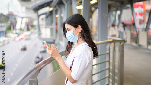 A young woman is wearing face mask in the Street city .