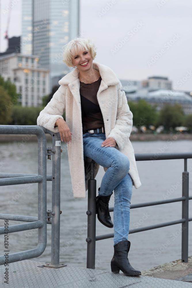 Blonde Frau im Mantel am Fluss Blonde Frau im Mantel am Fluss