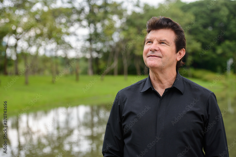 Portrait of happy mature handsome businessman relaxing at the park Portrait of happy mature handsome businessman relaxing at the park