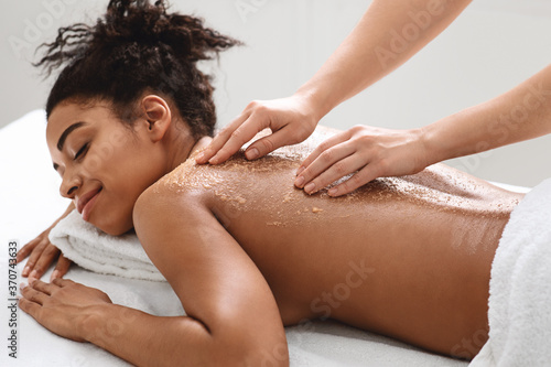 Canvas Print Spa therapist scrubbing black woman skin, using natural beauty products