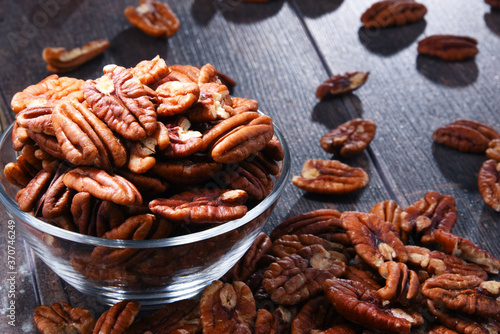 Bowl with pecan nuts on wooden table.