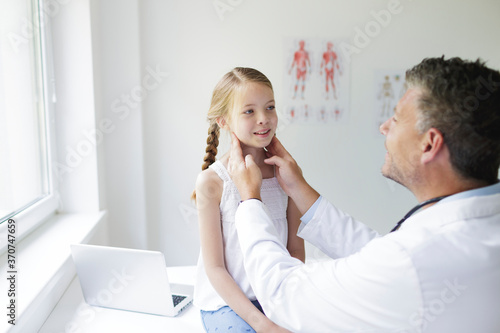 Doctor in white coat examines young, pretty girl in his practice or in a hospital