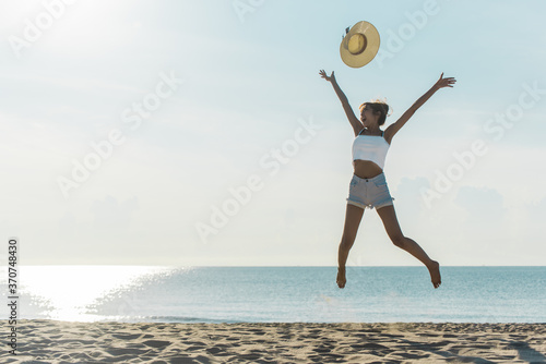 Full Length Of Woman With Arms Outstretched Jumping On Shore At Beach