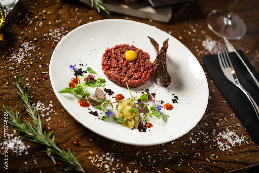 Steak tartare. Horseradish creme, black bread, baguette chips on white plate. Delicious healthy raw meat food closeup served on a table for lunch in modern cuisine gourmet restaurant. Steak tartare. Horseradish creme, black bread, baguette chips on white plate. Delicious healthy raw meat food closeup served on a table for lunch in modern cuisine gourmet restaurant.