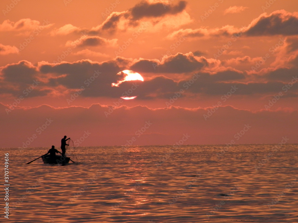 Silhouettes of fishermen at red sunset