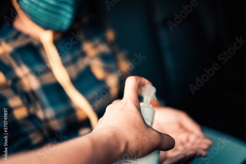 Woman cleaning a hand with 75% alcohol gel before driving through the screening to prevent Coronavirus or Covid-19