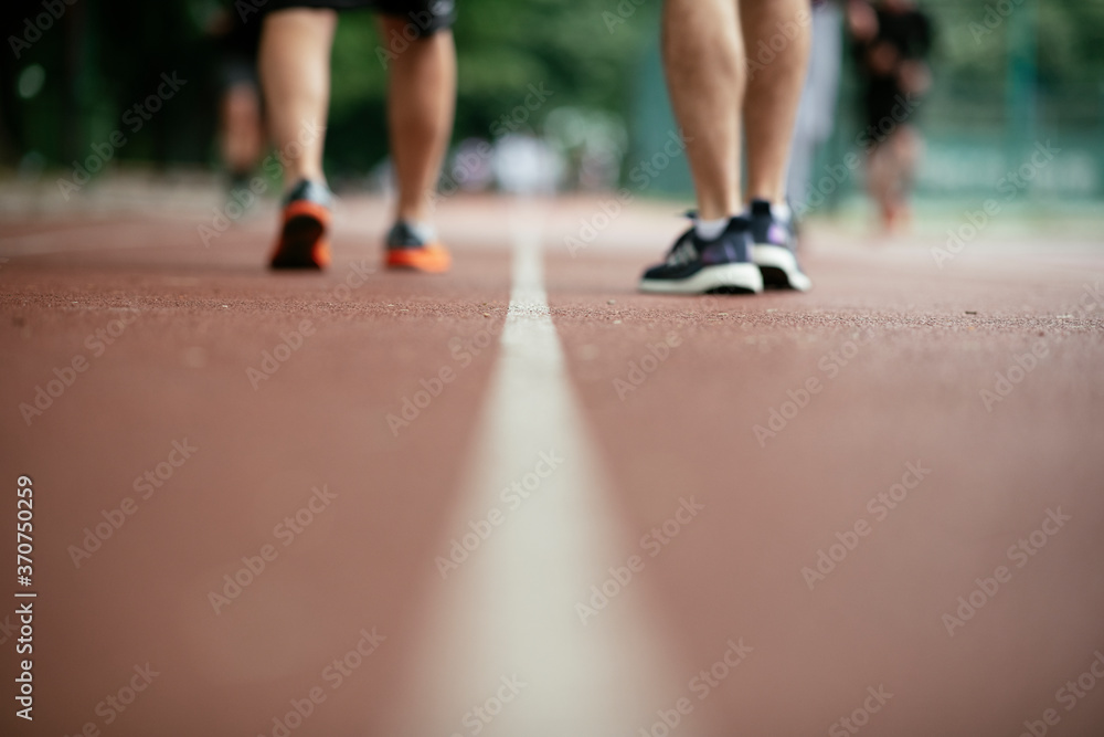 Young men training on a race track. Two young friends running on the athletics track.. Young men training on a race track. Two young friends running on the athletics track..
