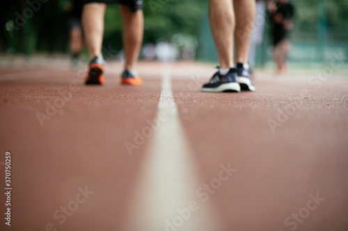 Young men training on a race track. Two young friends running on the athletics track.. © JustLife