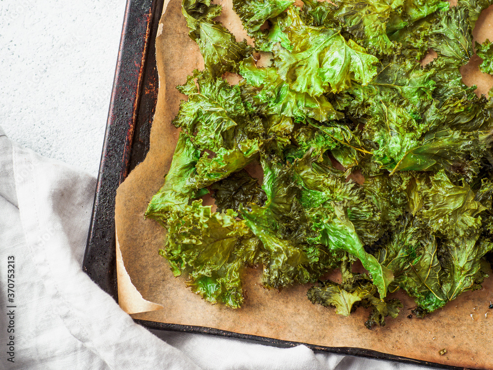Green Kale Chips with salt on oventray. Homemade healthy snack for low