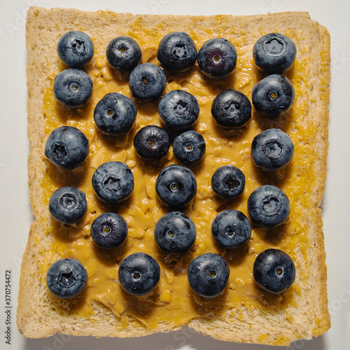 Toast with peanut butter and blueberries on a white plate. View from above