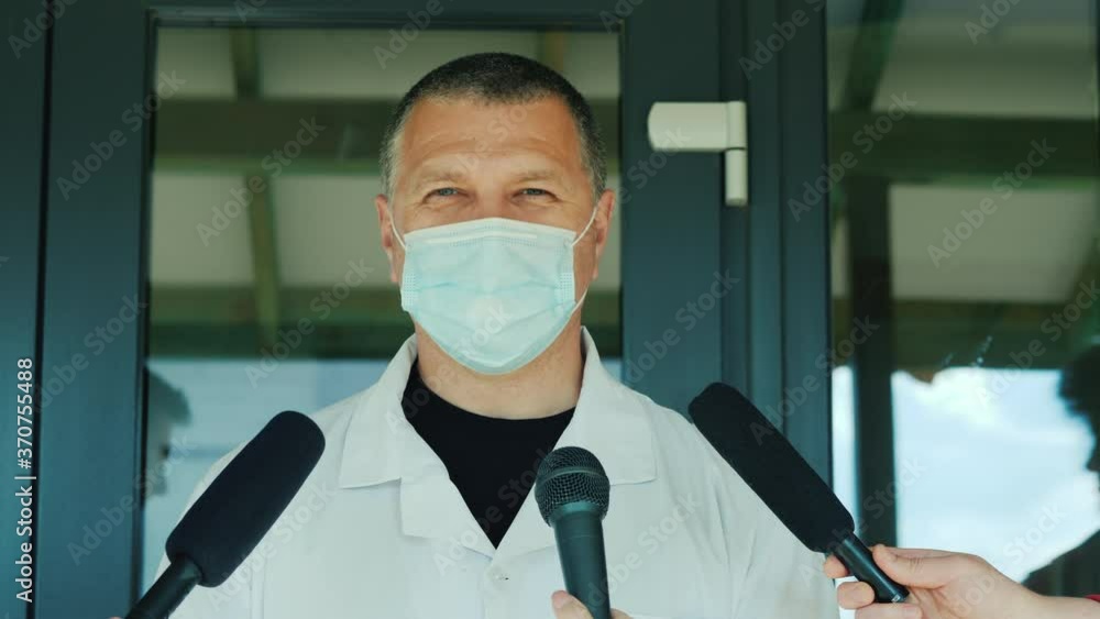 A doctor in a protective mask tells the news to reporters A doctor in a protective mask tells the news to reporters