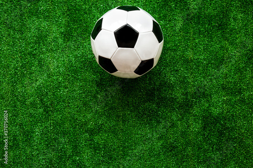 Football ball on green grass background top view copy space