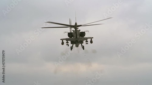 AH-64 Apache helicopter firing gun while hovering