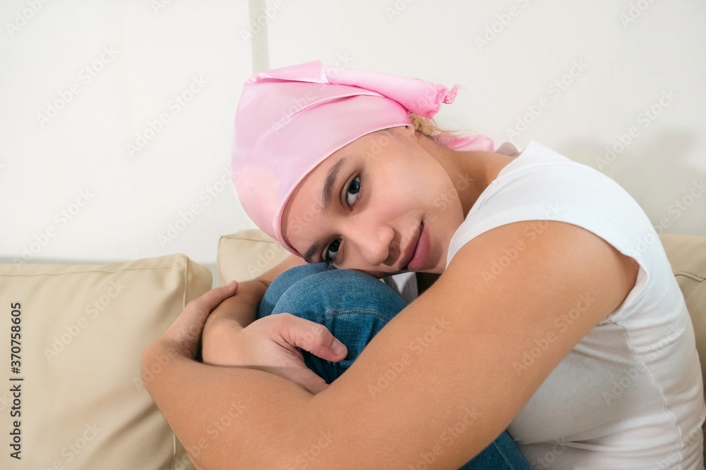 Woman with cancer sitting after chemotherapy sessions. Portrait of young woman facing the side effects of hair loss. Woman with cancer sitting after chemotherapy sessions. Portrait of young woman facing the side effects of hair loss.