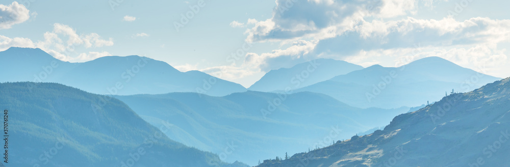 Mountain ranges in blue haze, evening light, panoramic view. 